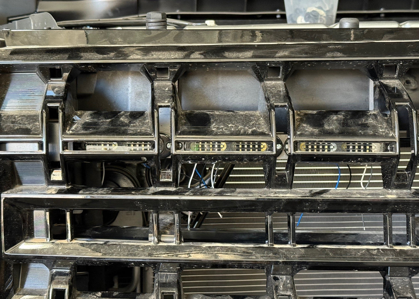 Bracket with three whelen t-series lights mounted behind the grille of a 2025 tahoe