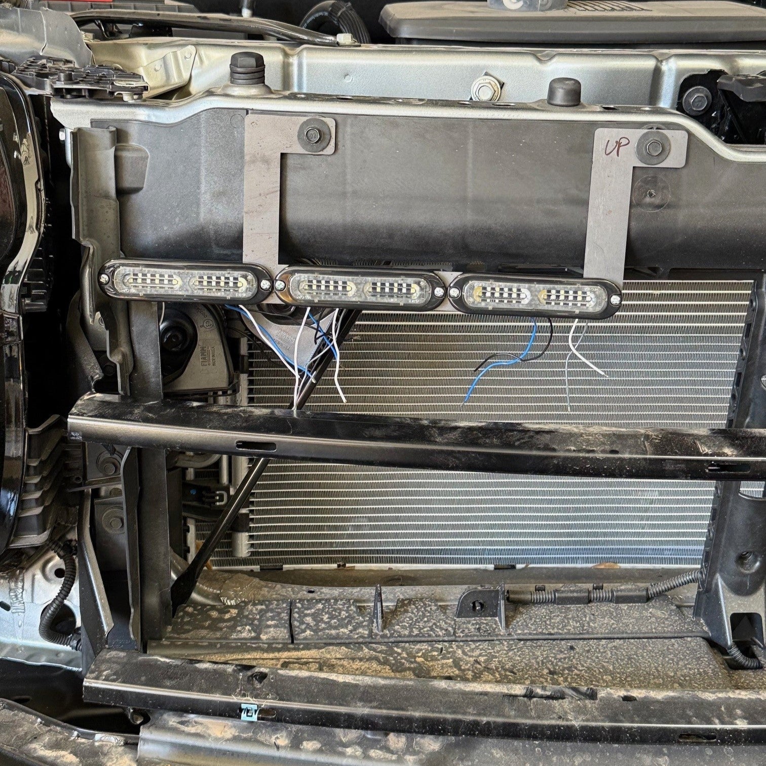 Bracket with three whelen t-series lights behind the grille of a 2025 tahoe.